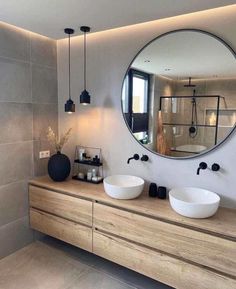 a bathroom with two sinks and a large round mirror on the wall next to it