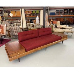 a red couch sitting on top of a wooden table in a room filled with furniture