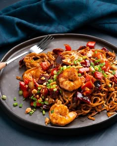 a plate full of noodles and shrimp with chopsticks next to it on a table