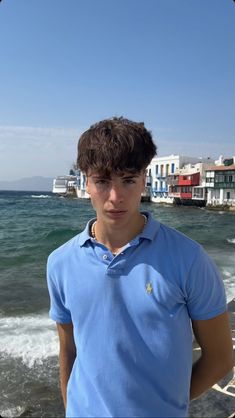 a young man standing on top of a beach next to the ocean