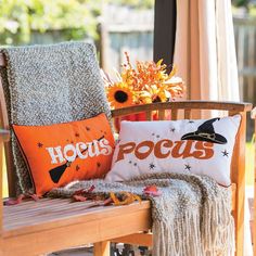 an orange pillow sitting on top of a wooden chair next to a vase with flowers