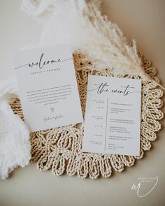 the wedding stationery is laid out on top of a doily with a feather