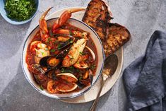 a bowl filled with seafood next to bread