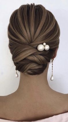 a woman with her hair in a low bun and two pearls on the back of her head