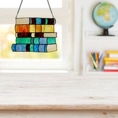 a stained glass chandelier hanging from a chain on a table in front of a window