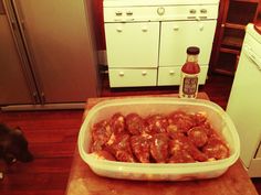 a large container filled with meat sitting on top of a wooden table next to a dog