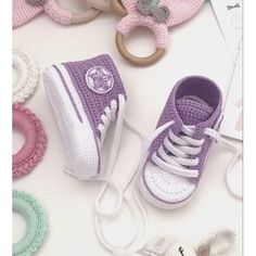 crocheted baby shoes and pacifiers are on the table