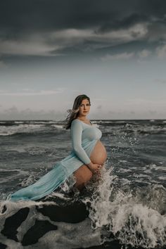 a pregnant woman is standing in the ocean