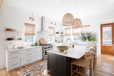 a kitchen with white cabinets and black island in front of a stove top oven next to a dining room table