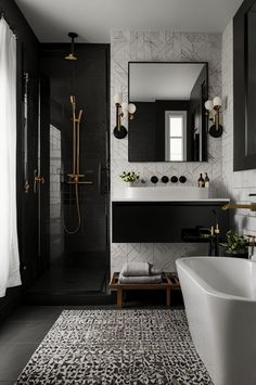 a black and white bathroom with a large bathtub next to a sink, mirror and shower