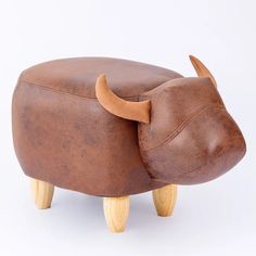 an animal shaped stool with wooden legs and a cow head on it's back