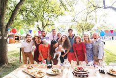 a group of people standing around a table with food on it and balloons in the background