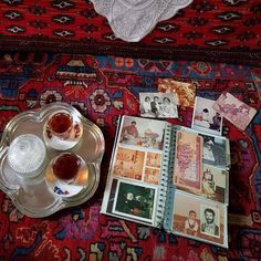 two cups of tea on a tray next to an open book with pictures and photographs