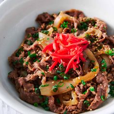 a close up of a bowl of food with meat and vegetables in it on a table