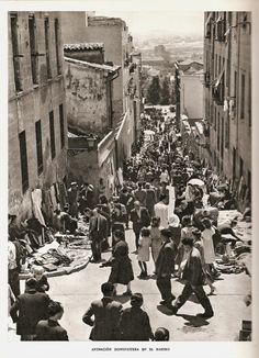 an old black and white photo of people walking down a street with clothes on the ground