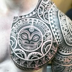 a man's chest with an intricate tattoo design on his arm and shoulder is shown