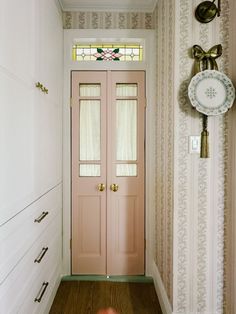 a pink door in a white room next to a clock