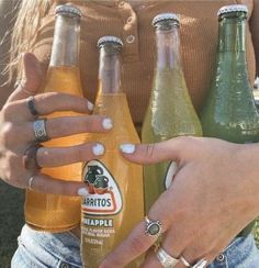 a woman holding three bottles of beer in her hands and two fingers on the bottle