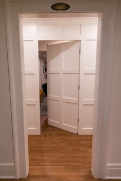 an open door leading to a living room with hard wood flooring and white walls