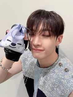 a young man is holding up a blue and white object to his face while wearing black gloves