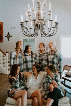 a group of women sitting on top of a couch in front of a chandelier