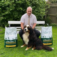 a man sitting on a bench with his dog and two bags of cat litter next to him