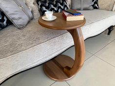 a wooden table sitting on top of a white floor next to a couch with pillows