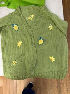 a green sweater with lemons on it next to a pair of shoes