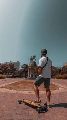 a man riding a skateboard on top of a red brick road next to a statue