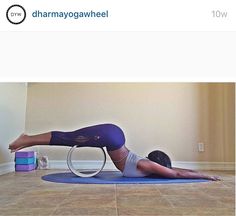 a woman is doing yoga on a blue mat with a white hoop in front of her