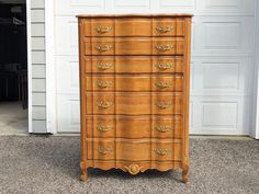 an old wooden dresser with gold handles in front of a garage door and white doors