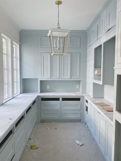 an empty kitchen is shown with white cabinets and gray counter tops, while the light fixture hangs from the ceiling