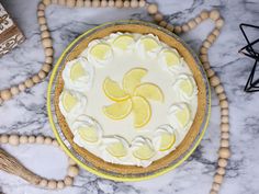 a lemon pie with white frosting and sliced lemons on the top sits on a marble table