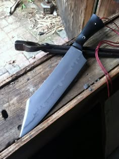 a large knife sitting on top of a wooden table next to a string tied around it