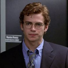 a young man wearing glasses and a suit