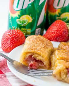 a piece of pie on a plate with strawberries and two cans of soda in the background