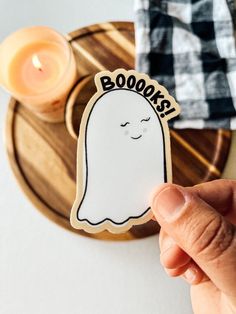 a person holding up a sticker with a ghost on it