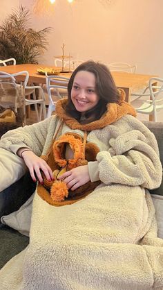 a woman sitting on a couch with a stuffed animal in her lap and smiling at the camera