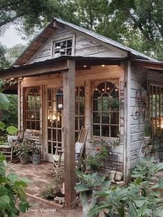 a small building with lots of windows and plants in the front yard, surrounded by greenery