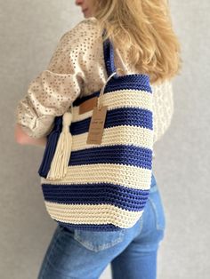 a woman carrying a blue and white crochet bag with a tag on it