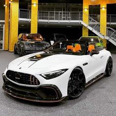 two white sports cars parked next to each other in front of a yellow and black building