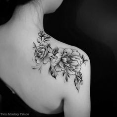 a woman's shoulder with flowers on it and leaves around the neck, in black and white