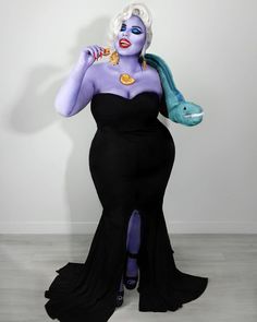 a woman in a black dress with purple hair and blue makeup is holding a fish