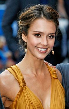 a close up of a person with a smile on their face and hair in a bun