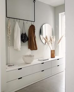 a white room with two mirrors and coat racks