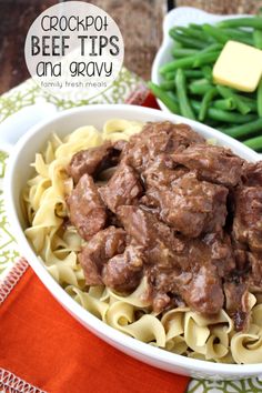 beef tips and gravy in a white bowl with green beans on the side