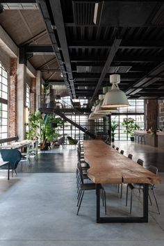 a long wooden table sitting in the middle of a room with lots of windows and chairs