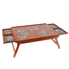 a wooden table with two trays on it and blue flowers painted on the top