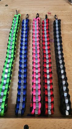 several different colored lanyards are lined up on a wooden table with metal clasps