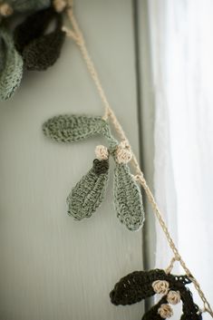 crocheted leaves hang on a rope next to a window